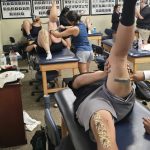 People receiving tattoos in a busy tattoo studio.